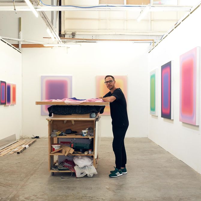 artist Jonny Niesche stands by a wall in his studio