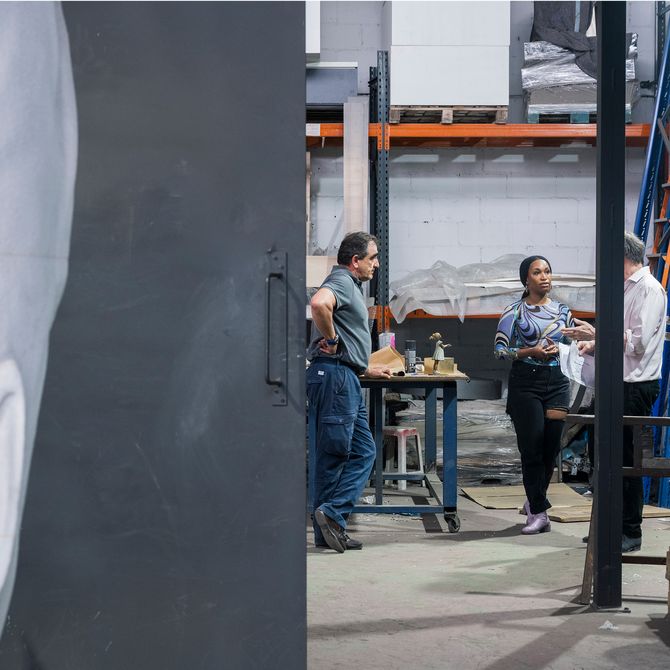 Three people engaged in discussion in a large, industrial workshop space