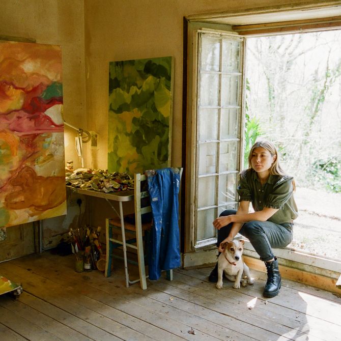 artist sat crouching on her windowsill with her dog in her studio