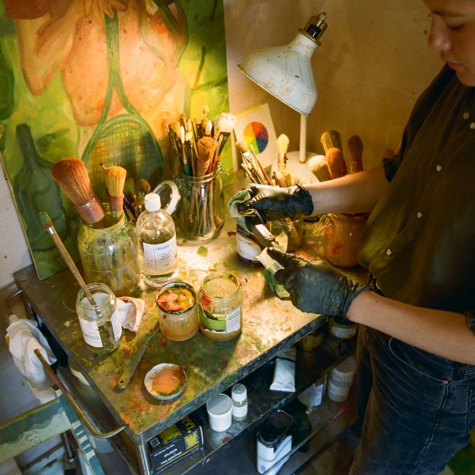 a view looking down on the artist as she selects paints and brushes from a table