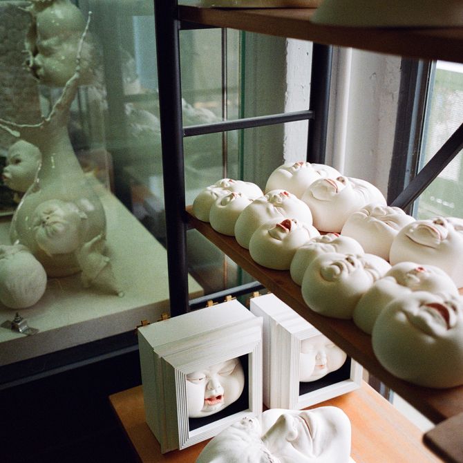 a row of sculpted heads with unique, varying expressions lined up on a shelf