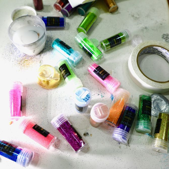 bird's eye view of a collection of tubes of glitter and a paintbrush and roll of tape