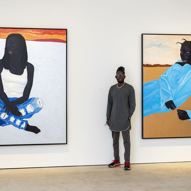 Kwesi Botchway standing in front of two figurative paintings