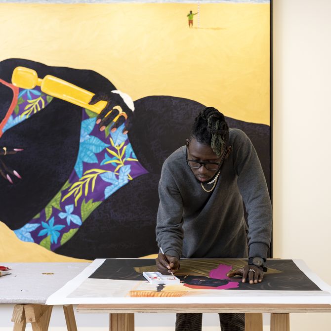 Kwesi Botchway leaning forwards to work on a print on a table 