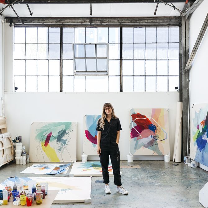 Heather Day standing in her studio surrounded by large canvases