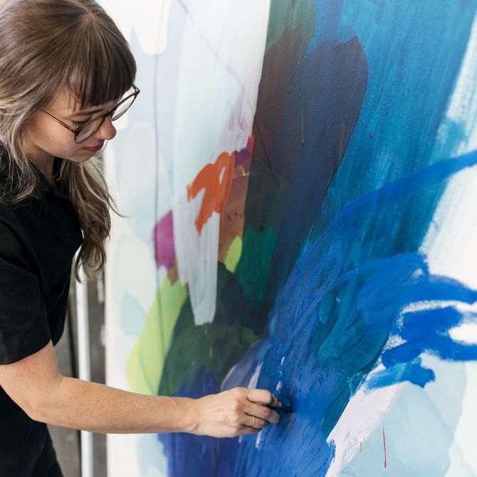 Heather Day adding blue detail to a canvas in front of her