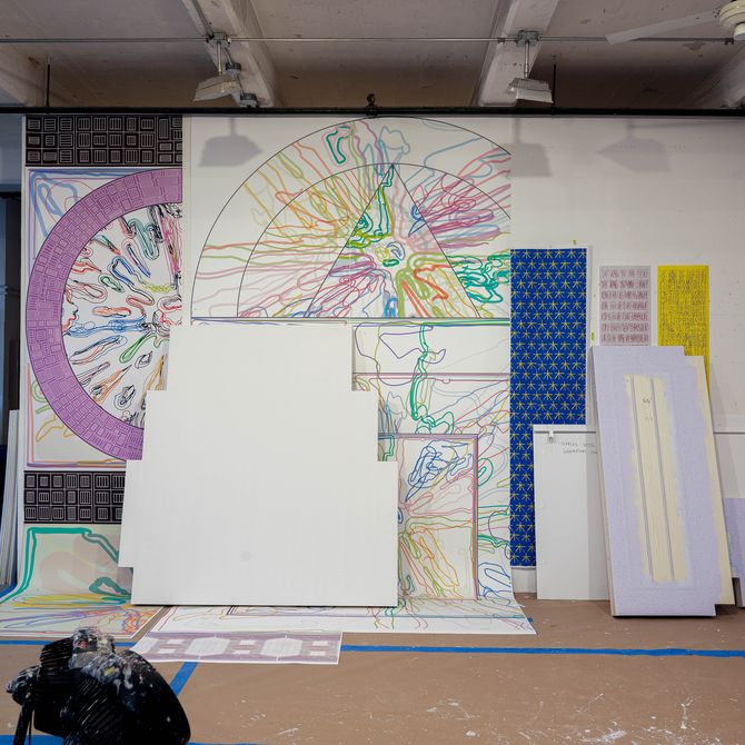 Artworks by Peter Halley stacked against different walls of his studio