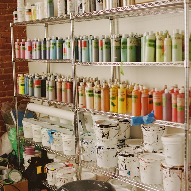 Shelves filled with paint pots and tubes in Hebru Brantley's studio