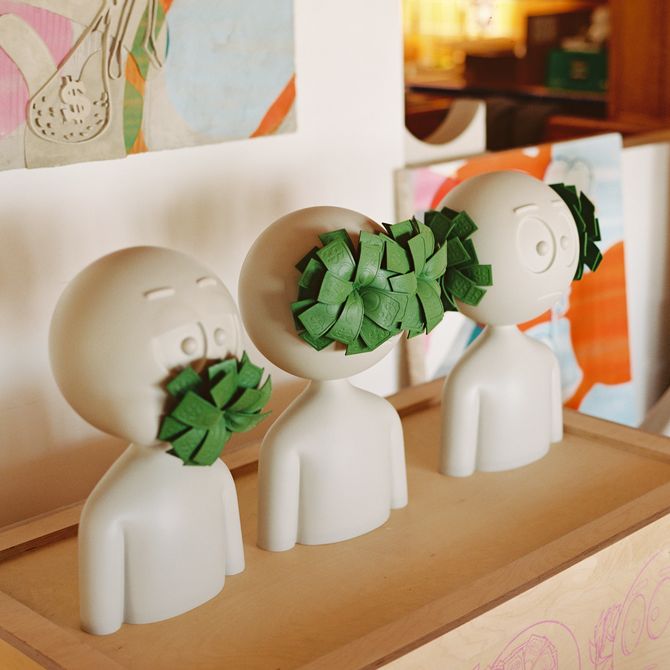 three cartoon busts by artist Kai lined up on a box