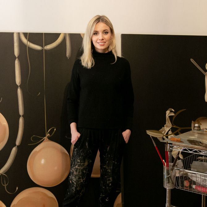 Anna Weyant stands in front of her paintings