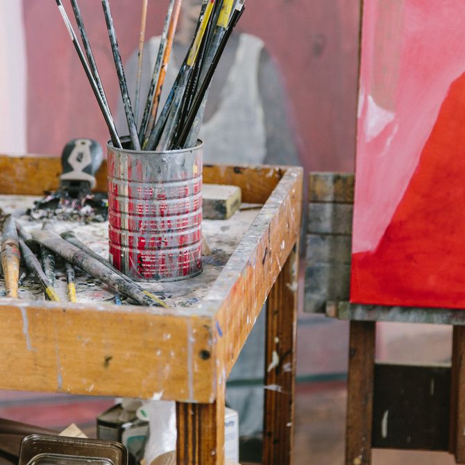 paint brushes in a pot on a table in the artist's studio