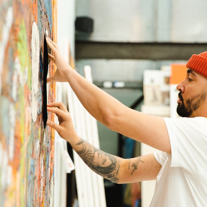Angel Otero placing his hands on a large-scale painting