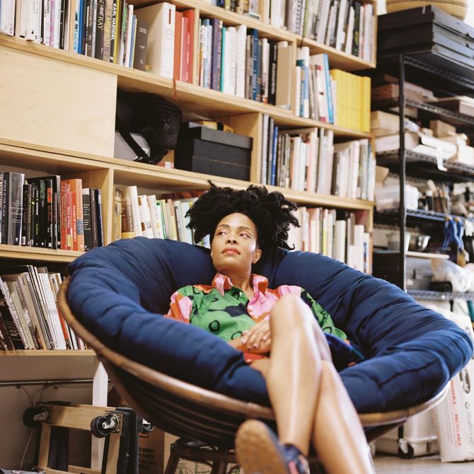 Kenturah sitting in a blue chair in front of a book case