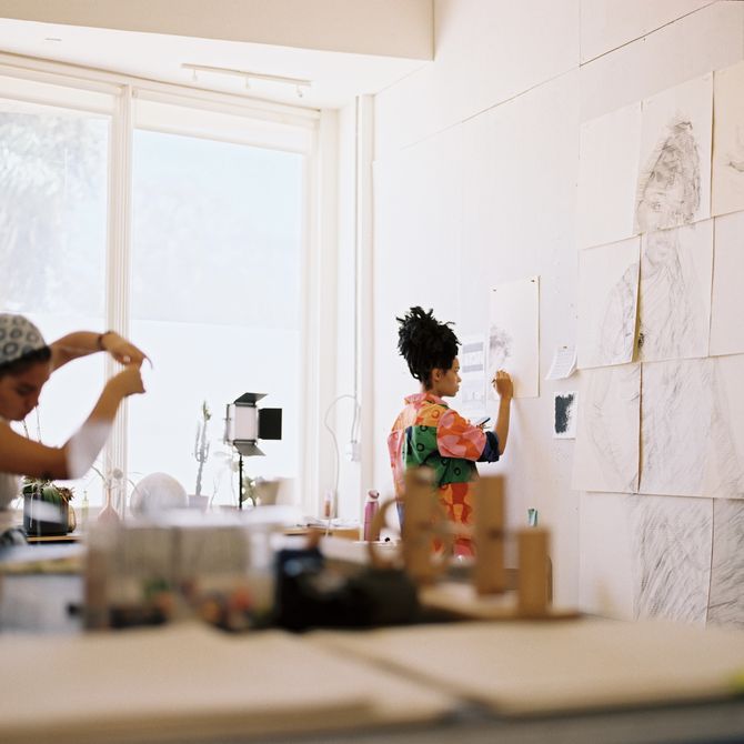 Kenturah drawing on paper against the wall in her studio
