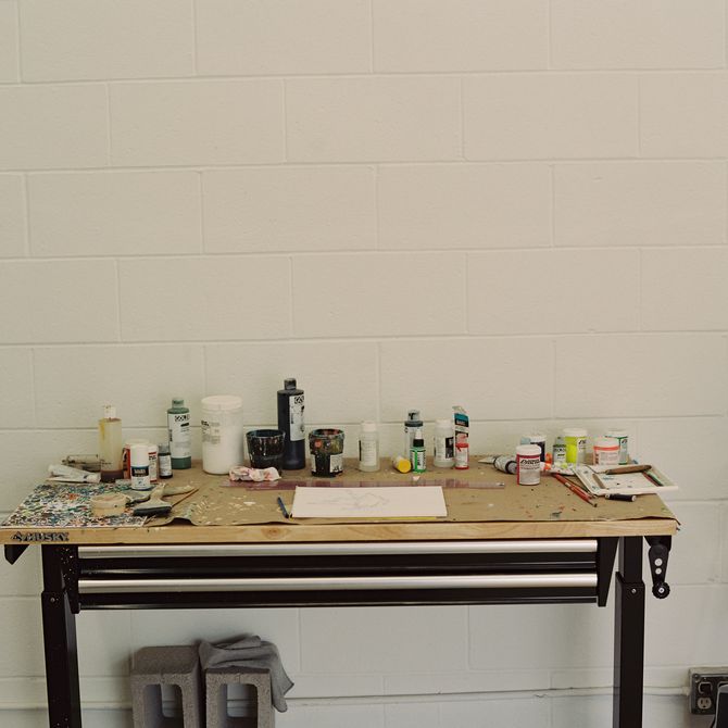 table in the artist's studio with various tools and pots of paints and ink on it