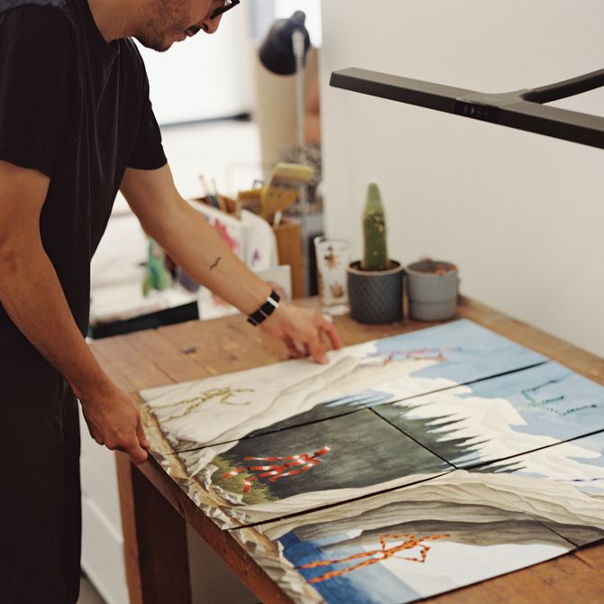 artist holding and looking over a selection of works on his desk in his studio