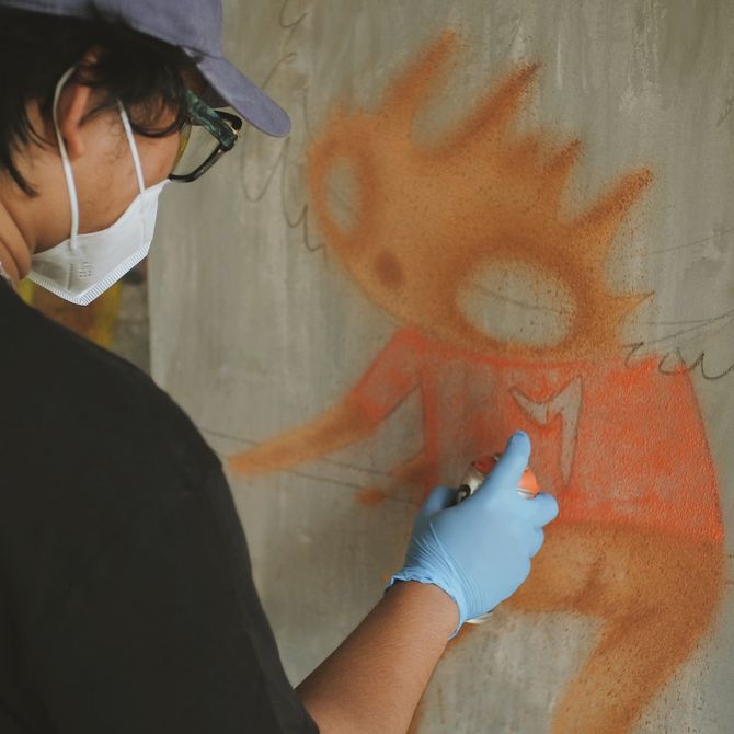 Ryol spraying orange aerosol onto an outline of the wall
