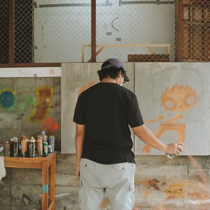 artist Ryol with his back turned to the camera, spraying an aerosol 