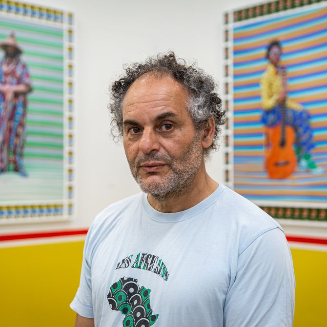 artist stood in front of two of his paintings looking into the camera