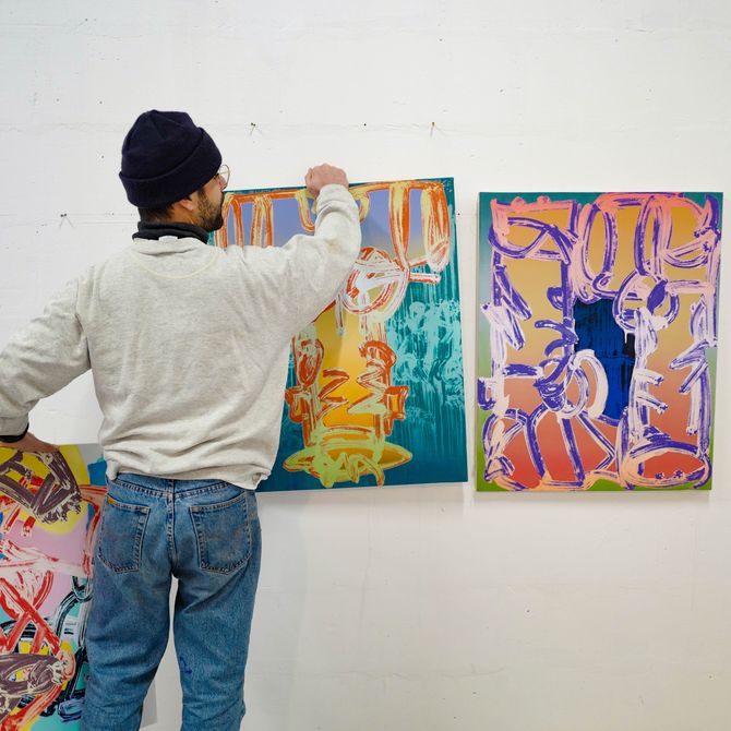 Pablo Tomek arranging a selection of paintings in his studio