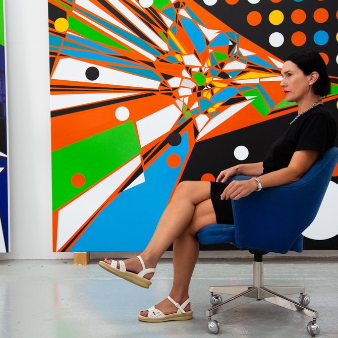 Sarah Morris sitting in front of her paintings