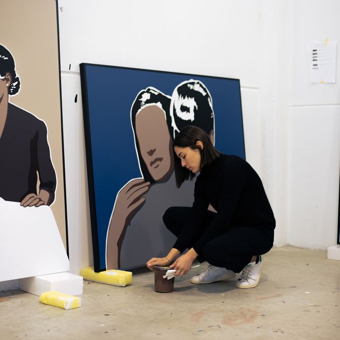 adriana oliver crouching by paintings in studio