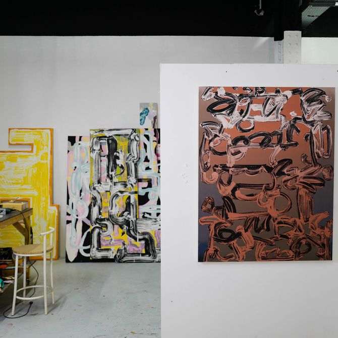 large paintings filling the white walls of a studio