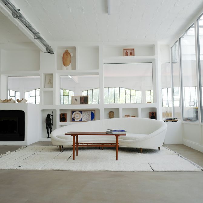 A white sofa and wooden table sit in front of open cabinets in a bright room