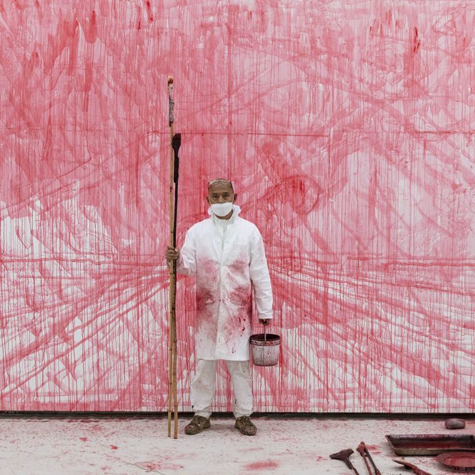 zhang huan stood in white apron with paint pot and long tool in front of red and white wall art
