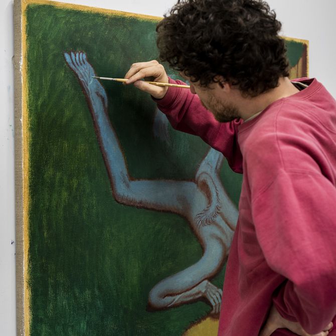 artist leaning over a painting he works on