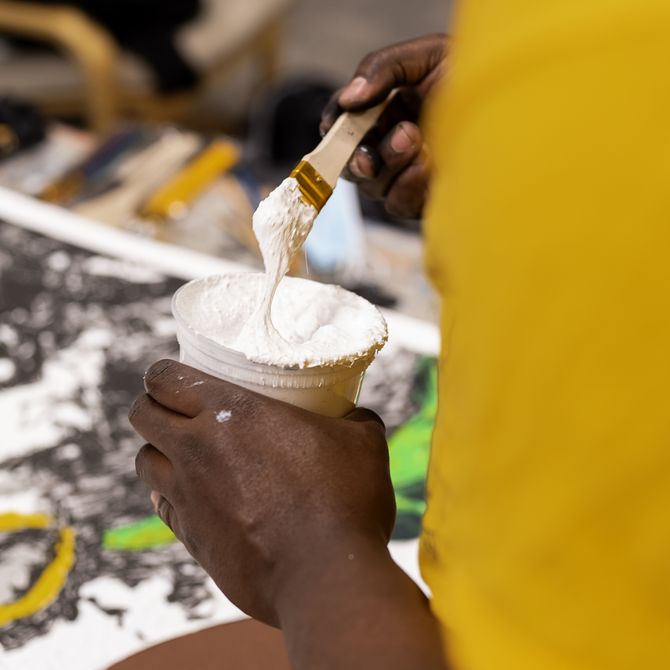 close-up of the artist handling thick white paint in a pot