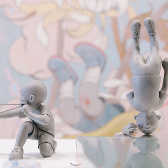 Close up of two James Jean sculptures set against a painting in background