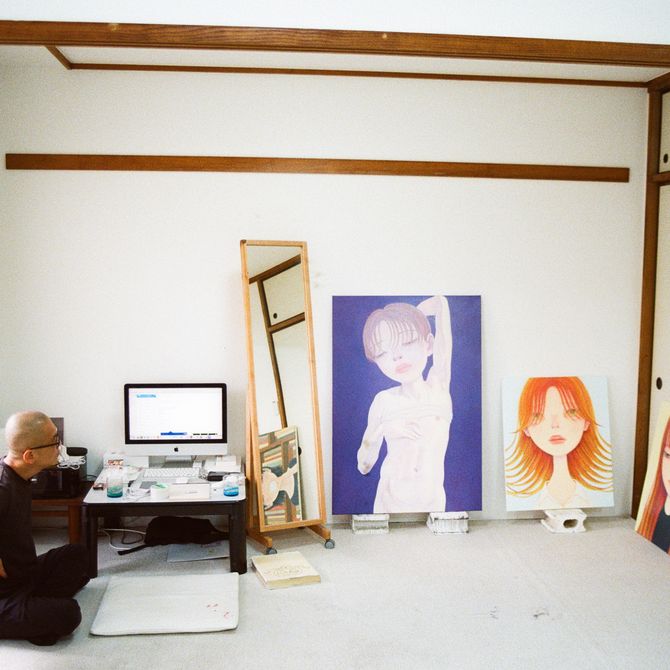 Hideaki sat on the floor of his studio with his paintings