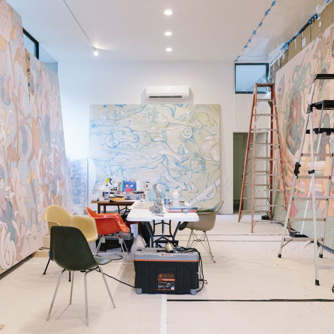 artist studio with three giant paintings on each wall and chairs and ladders