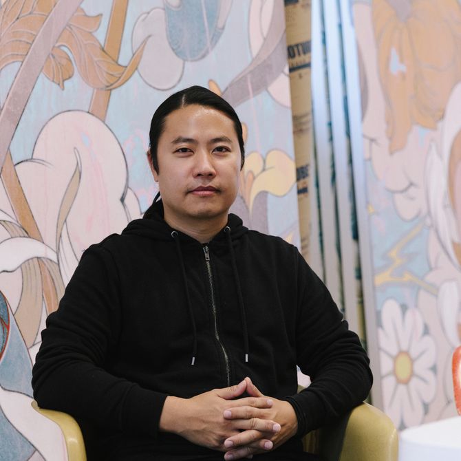 Portrait view of James Jean with painting behind him