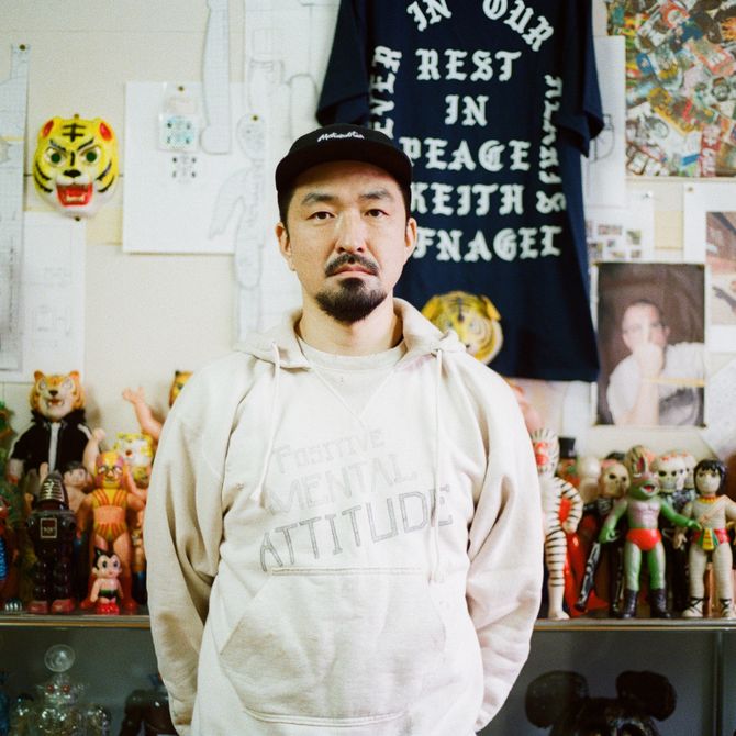 Haroshi standing in his studio with figurines behind him