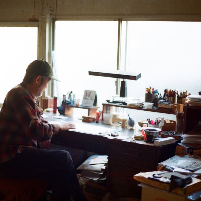 artist Tomoo Gokita sat at a desk in his studio