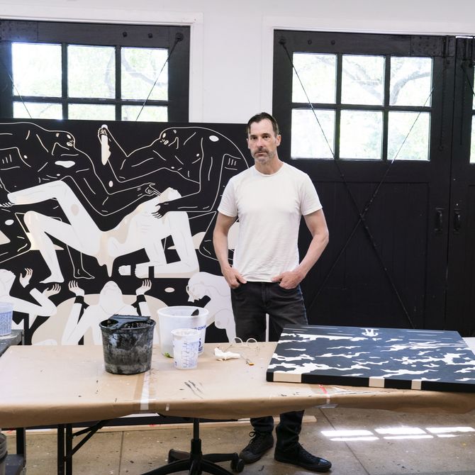 Cleon Peterson standing in his studio with paints and artworks