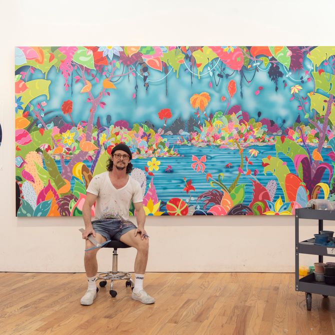 Erik Parker sits on stool in front of landscape large vibrant painting