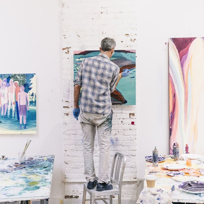 Jules de Balincourt standing on a chair working on a painting