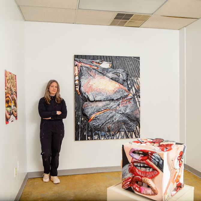 artist Gina Beavers leaning on a wall surrounded by artwork