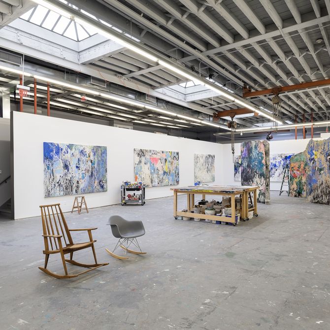 inside of an artist studio with chairs, desk and large scale paintings on the wall