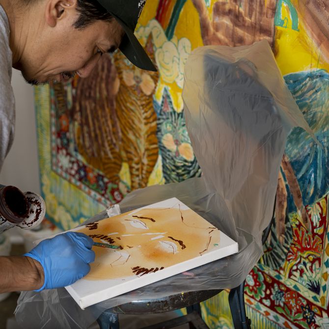 Koichi Sato paints small canvas infront of bigger one