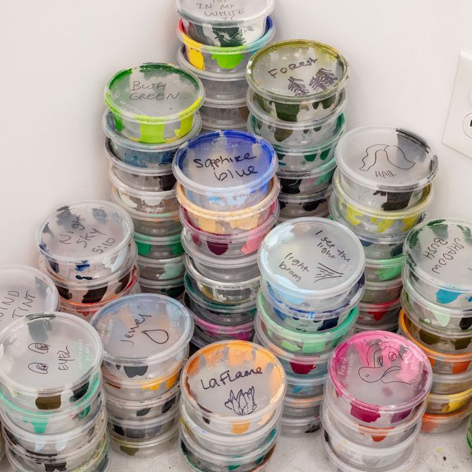 various coloured paint pots stacked up in a corner