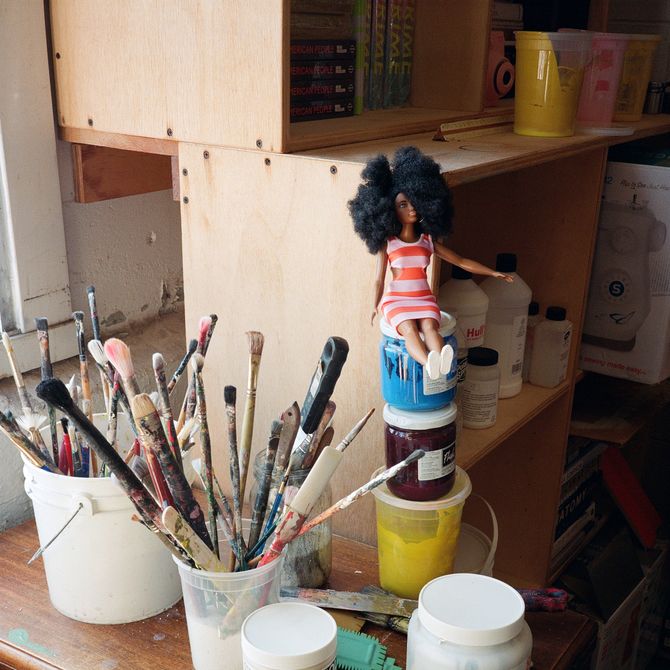 paint brushes and a barbie doll in a softly lit studio space