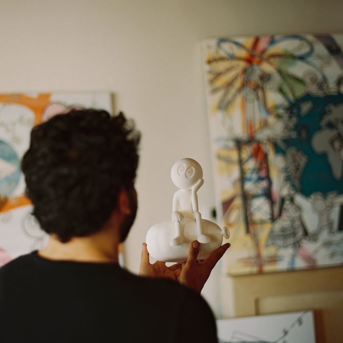 Arist Kai seen from behind looking at a small white sculpture