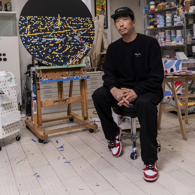 Yoon Hyup sitting in his studio next to one of his paintings