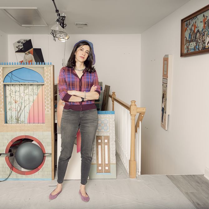 Arghavan Khosravi standing in front of a selection of her artworks