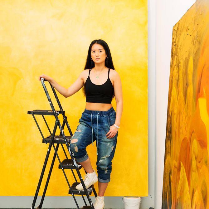 Dominique Fung standing on a ladder in her studio