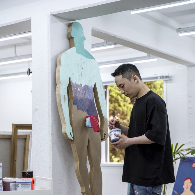 Hyangmok Baik standing in his studio, placing a paint brush into a paint pot
